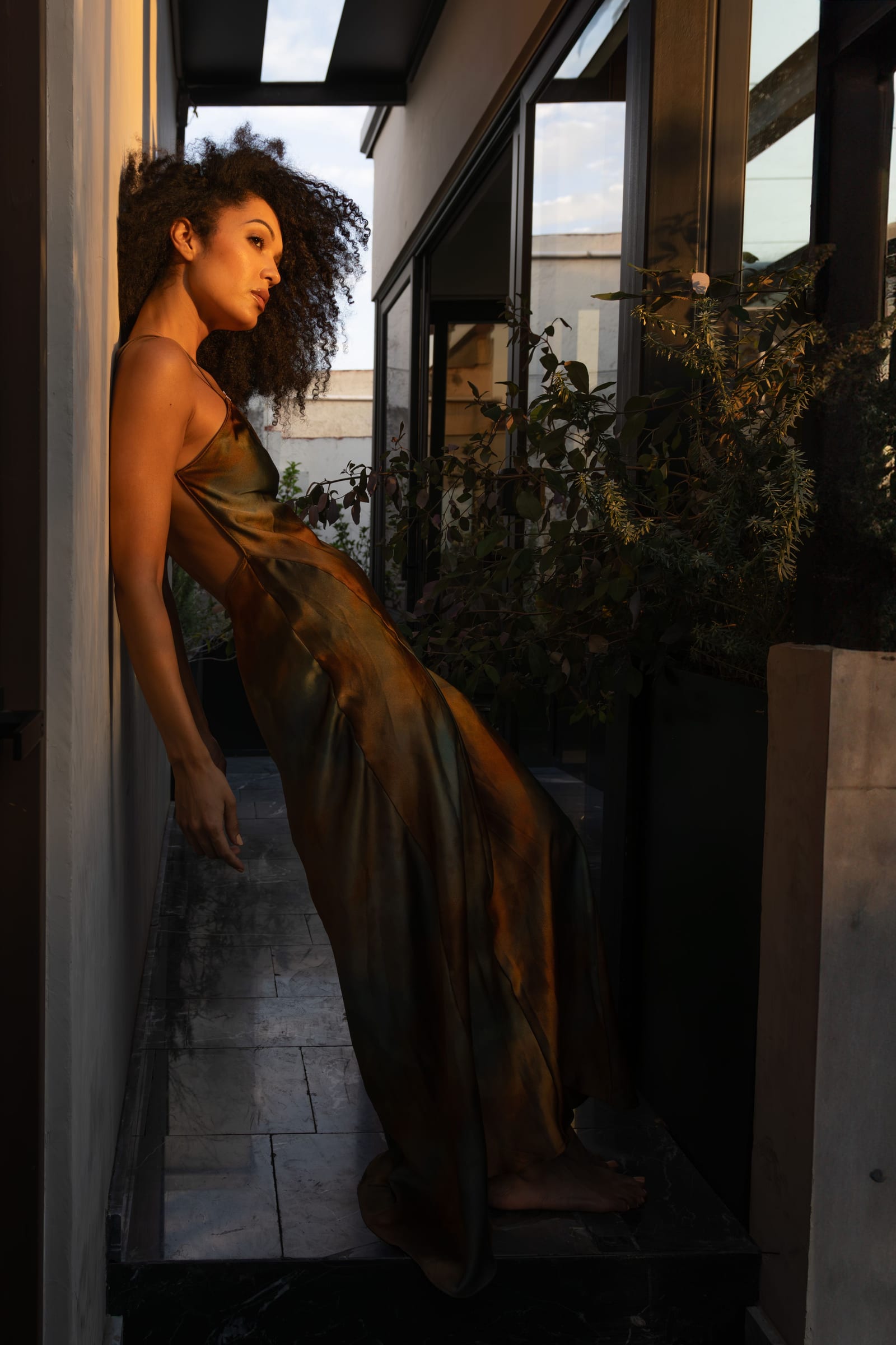 Elegant woman in a champagne satin dress and gold headpiece in warm window light