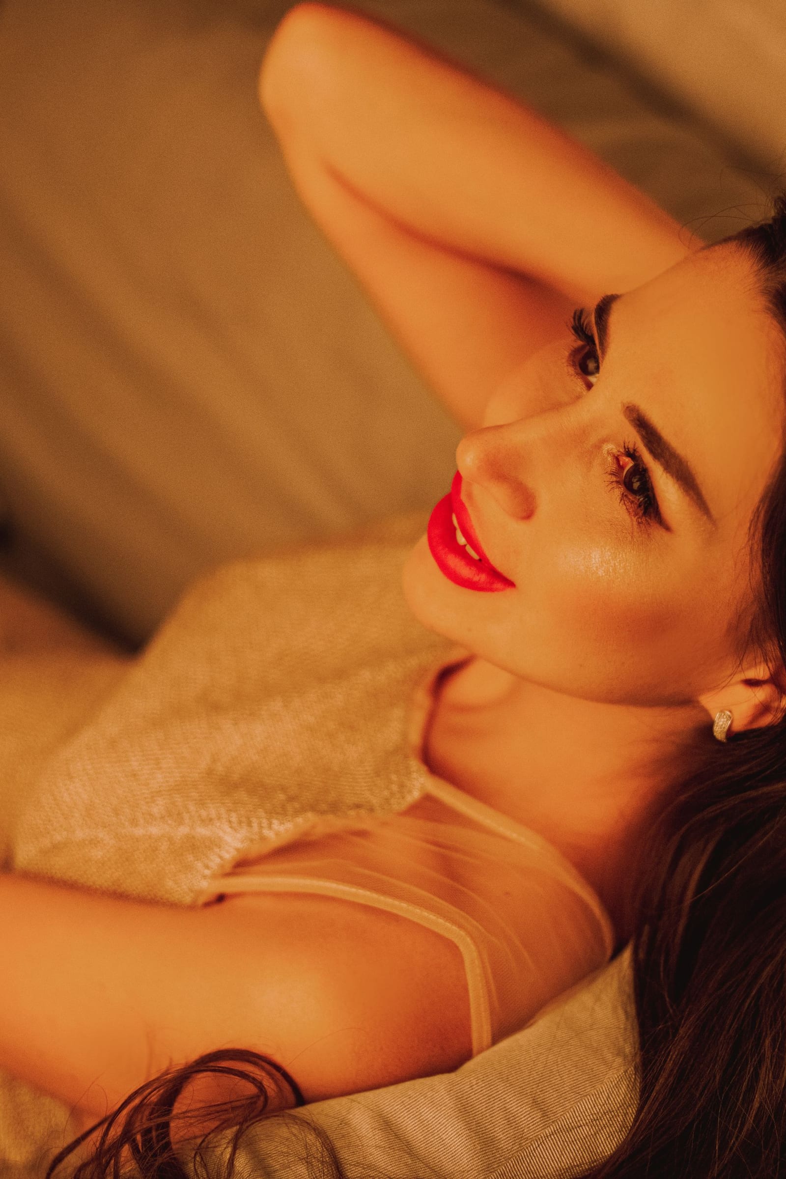 Woman with red lips on a sofa in warm amber light.