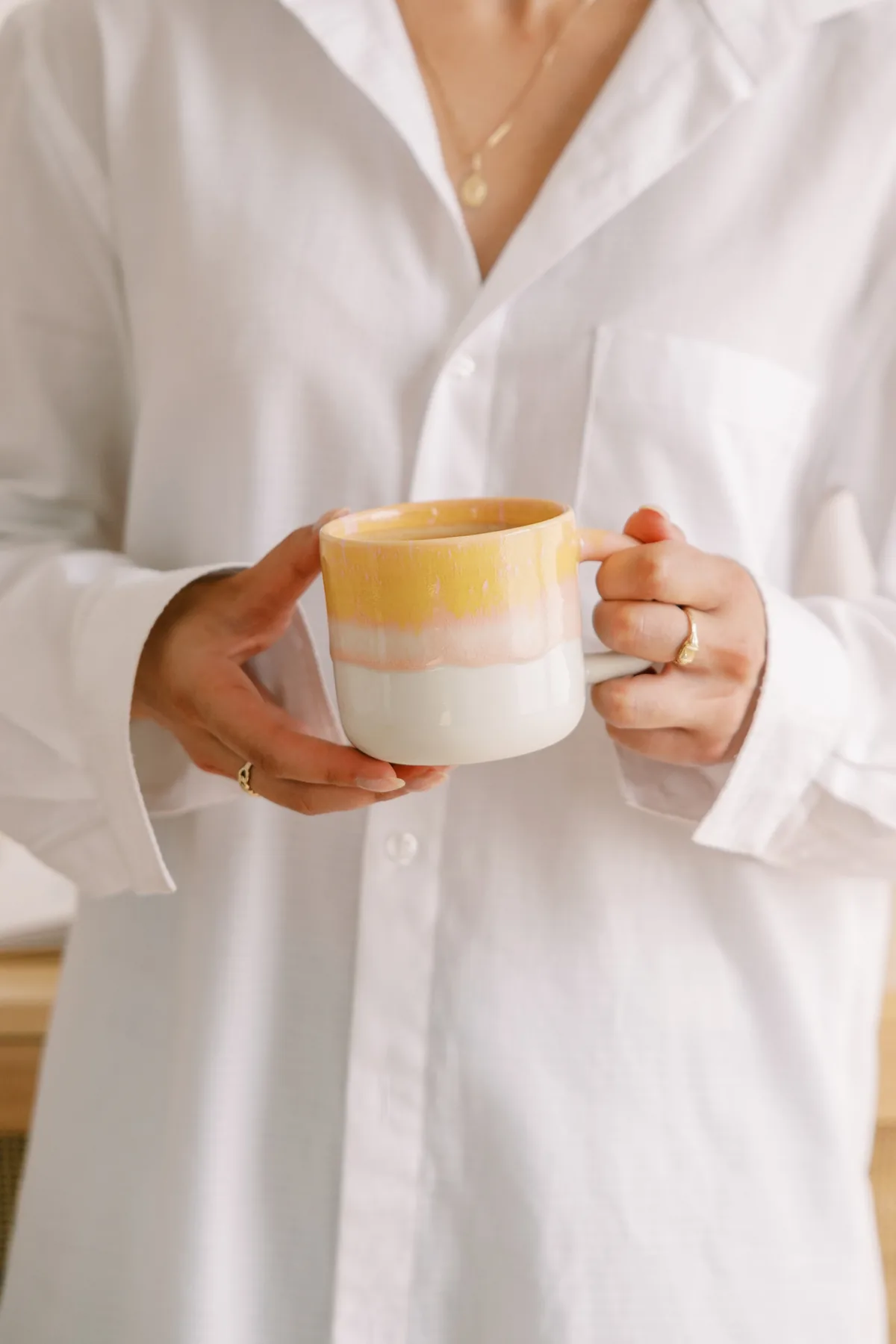 Woman in a white shirt holding a cup in sunlight